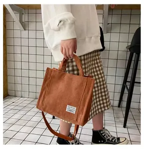 Detailed texture of caramel corduroy square tote bag with woven label and strap
