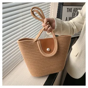 Détail du sac cabas en paille tissée avec rabat en cuir marron et fermeture bouton perle