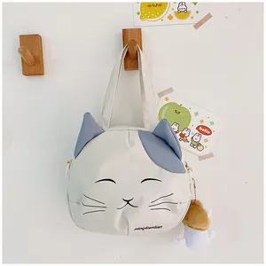 Close-up of cute cat canvas bag featuring cat ears and plush charm on white wall