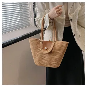 Détail du sac cabas en paille avec rabat en cuir et fermoir perle élégant pour femme