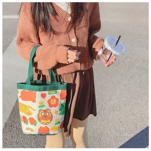 Detailed view of canvas lunch bag featuring cute cartoon tiger pattern and green handles