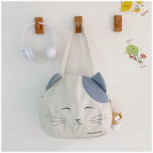 Detail of cute cat canvas tote bag featuring embroidered face and plush lion pendant