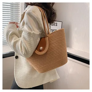 Détail du sac seau tissé kaki avec rabat en cuir marron et fermoir en perle blanche
