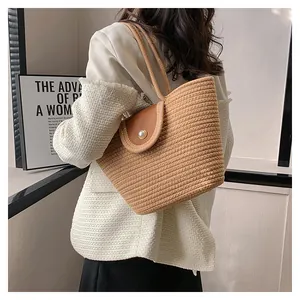 Détail d'un sac seau tissé avec rabat en cuir et fermoir à perle élégant sur l'épaule