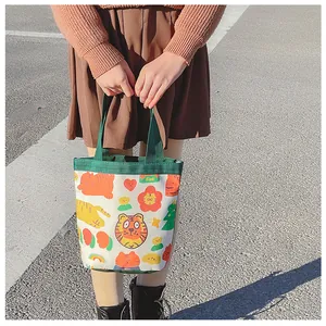 Detailed view of canvas lunch bag with cartoon tiger prints and green handles