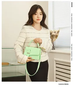 Detail van een muntgroene crossbodytas met vierkante gesp en handvat bovenop