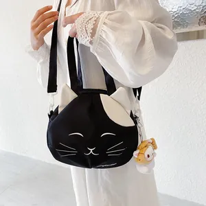 Cute cat-shaped canvas crossbody bag with white handles and a yellow plush charm