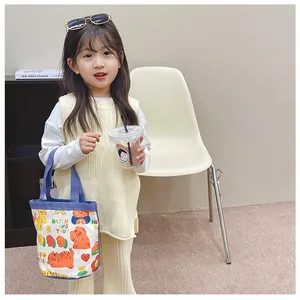 Close-up of a small canvas tote bag with cute cartoon cats and purple handles for kids