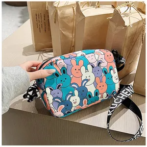 Detail of cartoon crossbody bag featuring colorful rabbit prints and a wide logo strap
