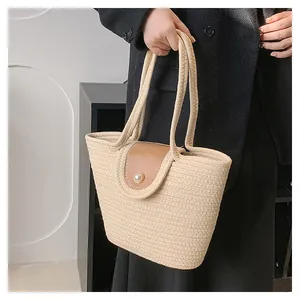 Détail du sac seau tissé avec rabat en cuir marron et grand fermoir en perle