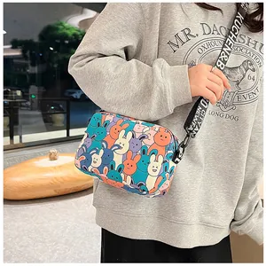 Detail of cartoon bunny print crossbody bag with lettered wide shoulder strap on model