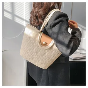 Détail du sac fourre-tout tressé avec rabat en cuir et fermeture par bouton perle blanc