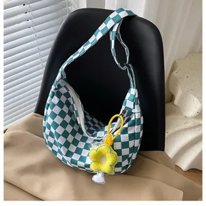 Detail der grün-weißen Segeltuchtasche mit kariertem Muster und gelber Plüschblume