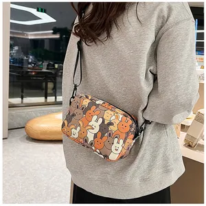 Detail of cartoon rabbit print shoulder bag on grey sweatshirt in a lifestyle setting