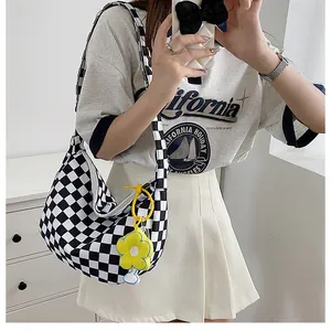 Details der karierten Hobo-Tasche aus Segeltuch mit Schultergurt und Blumenanhänger