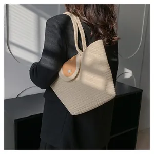 Détail du sac cabas tissé beige avec rabat en cuir marron et boucle perle sur le mannequin
