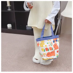 Close-up of cute cartoon cat illustrations on a small canvas tote with blue handles