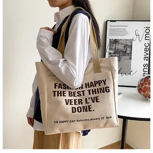 Detail of cream canvas tote bag with brown text print and durable khaki straps