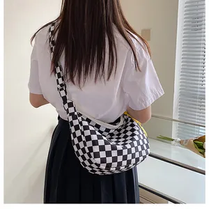 Nahaufnahme der Schachbrett-Segeltuchtasche mit breitem Gurt auf der Schulter