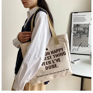 Close-up of cream canvas tote bag with black typography and brown woven handles