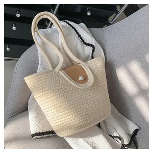 Détail du sac fourre-tout tissé avec bouton perle et rabat en cuir marron élégant