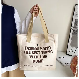 Detail of canvas tote bag with snap pocket and brown letter print in cream color