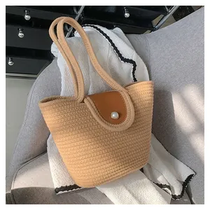 Détail du sac cabas tissé beige avec fermoir perle sur un rabat en cuir marron