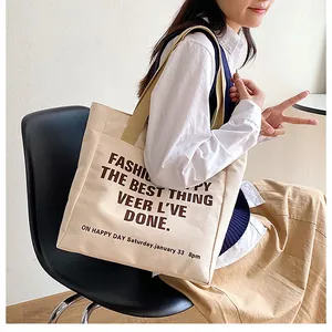 Detail of minimalist canvas tote bag with brown handles and vintage lettering print