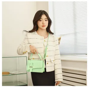 Muntgroene crossbodytas met gesp, gestyled met een crèmekleurig jasje en zwarte rok