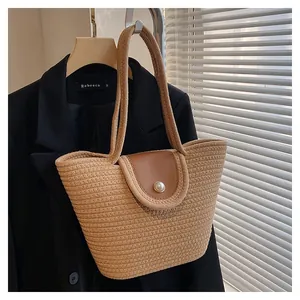 Détail d'un sac cabas tissé avec un rabat en cuir et une boucle en perle élégante