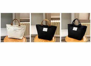 Three bucket canvas handbags in beige and black with minimalist bear print on wooden tray