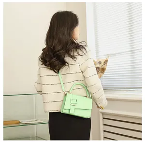 Lichtgroene crossbodytas met gesp getoond op model in een minimalistische setting