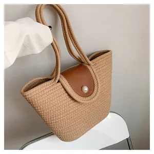 Détail de la texture en raphia tressé avec rabat en cuir et fermoir perle du sac cabas