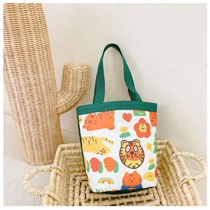 Detail of a small canvas lunch bag with cartoon animal prints and green handles