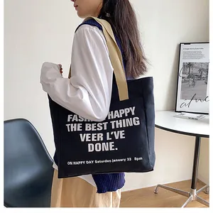 Detail view of large black canvas tote bag with cream straps and white art text