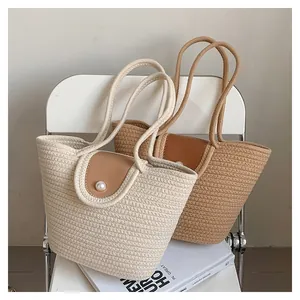 Détail du sac seau tissé avec élégante fermeture à bouton perle et rabat en cuir