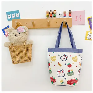 Detail view of a cute canvas tote bag with rabbit prints hanging on a wooden hook