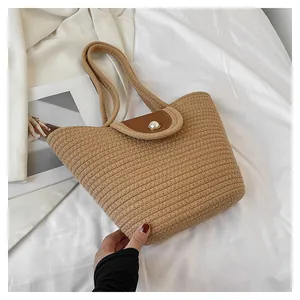 Détail du sac cabas en paille tissée avec rabat en cuir et fermoir en perle élégant