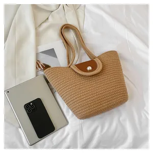 Détail du sac cabas tissé avec fermeture à bouton perle et finitions en cuir marron