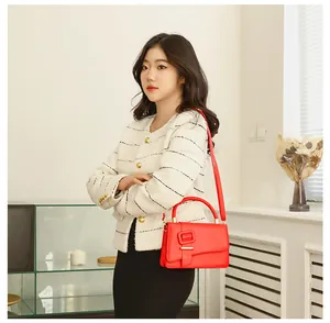 Detail van rode lederen crossbodytas met decoratieve vierkante gesp en goudkleurige hardware