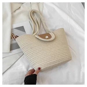 Détail du sac cabas tressé crème avec rabat en cuir et fermoir perle élégant