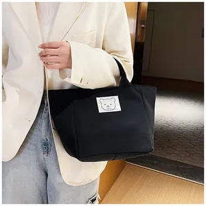 Close-up of black canvas bucket tote bag featuring a cute white bear patch on the front