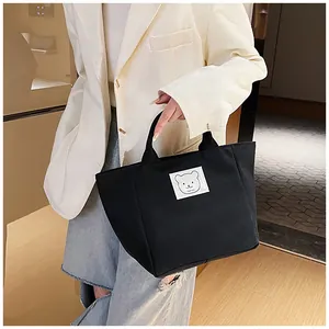 Detailed side view of a black canvas bucket bag with cute bear embroidery and sturdy handle