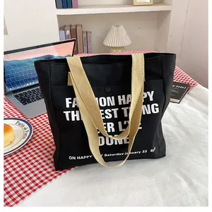 Detail of black canvas tote bag with beige strap and decorative white print text