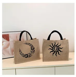 Detalle de bolsos tote de yute con estampados de sol y luna y asas negras