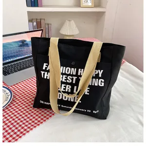 Detail of black canvas tote bag showing the front pocket with snap button and text print