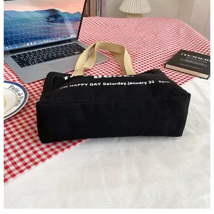 Detail of black canvas tote bag with beige handles on a checkered tablecloth