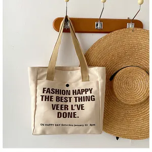 Detail of canvas tote bag hanging on wooden hook with beige webbing handles and brown text