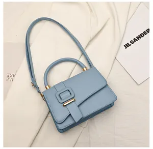 Detail van lichtblauwe crossbodytas met matte lederen textuur en grote gesp accent