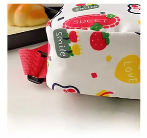 Detail der weißen Canvas-Kindertasche mit süßen Erdbeerdrucken und roten Trageriemen